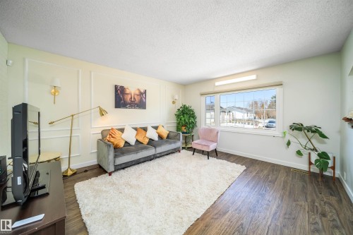Spacious living area featuring wood-finish flooring, a large window, and decorative wall molding - 5303 21 Avenue, Edmonton, AB - Indoor Photo Showing Living Room