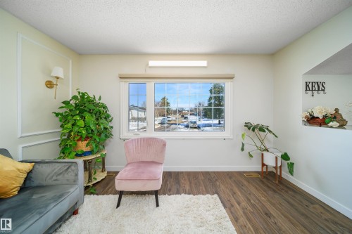 Bright living area featuring a large window, wood-finish flooring, and decorative wall molding - 5303 21 Avenue, Edmonton, AB - Indoor