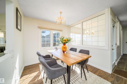 Dining area featuring wood-finish flooring, white walls, and a crystal chandelier - 5303 21 Avenue, Edmonton, AB - Indoor Photo Showing Dining Room