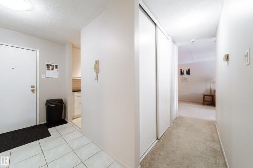 Entryway featuring ceramic tile flooring, a built-in closet with sliding doors, neutral wall tones, and overhead lighting - 220 14819 51 Avenue, Edmonton, AB - Indoor Photo Showing Other Room