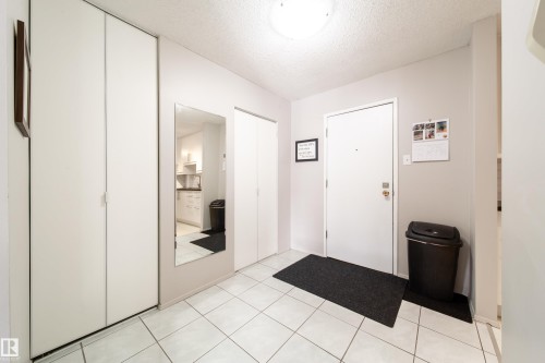 Entryway featuring white square tile flooring, a flush-mount ceiling light fixture, and light gray wall paint - 220 14819 51 Avenue, Edmonton, AB - Indoor Photo Showing Other Room