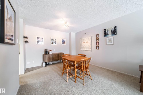 Spacious room with light-colored carpeting, smooth grey walls, and a textured white ceiling - 220 14819 51 Avenue, Edmonton, AB - Indoor