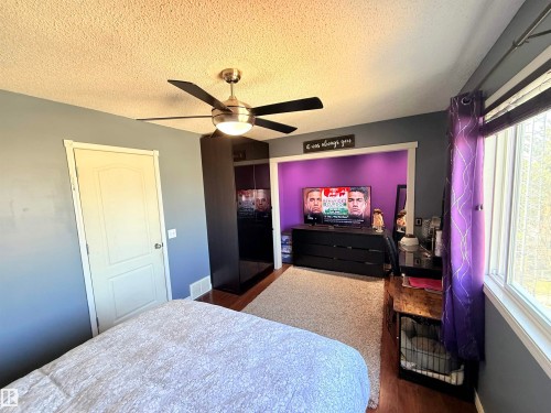 Bedroom featuring a ceiling fan with integrated lighting, wood-finish flooring, and a large window with blinds - 73 Birchmont Drive, Leduc, AB - Indoor Photo Showing Bedroom