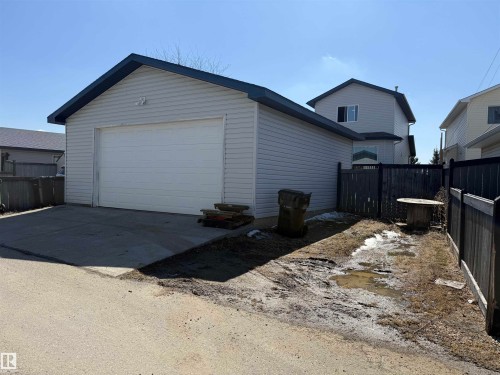 Detached garage featuring a white overhead door, light-colored horizontal siding, and a dark-colored roofline - 73 Birchmont Drive, Leduc, AB - Outdoor With Exterior