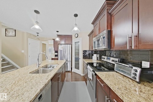 Spacious kitchen with granite countertops, rich wood cabinetry, stainless steel appliances, a double basin sink, and pendant lighting - 3609 Weidle Bend Bend, Edmonton, AB - Indoor Photo Showing Kitchen With Double Sink With Upgraded Kitchen