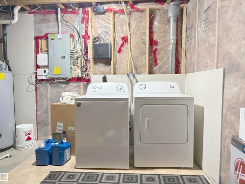 Utility area featuring a top-load washing machine, front-load dryer, exposed wall studs, thermal insulation, and an electrical service panel - 3609 Weidle Bend Bend, Edmonton, AB - Indoor Photo Showing Laundry Room