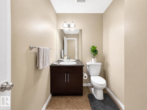Bathroom featuring a dark wood-finish vanity with a white basin, a mirror with sconce lighting, and a white toilet - 3609 Weidle Bend Bend, Edmonton, AB - Indoor Photo Showing Bathroom