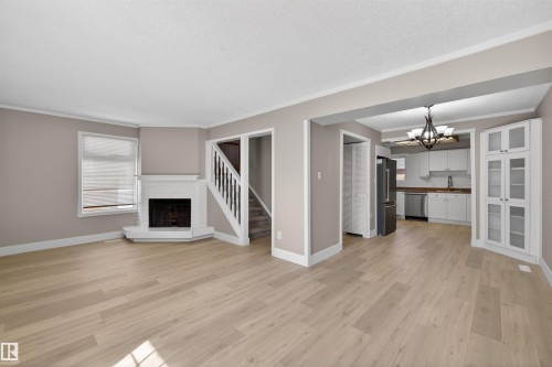 Light wood-finish flooring extending through an open-concept living area and kitchen - 11 Greenfield Estates, St. Albert, AB - Indoor Photo Showing Other Room With Fireplace