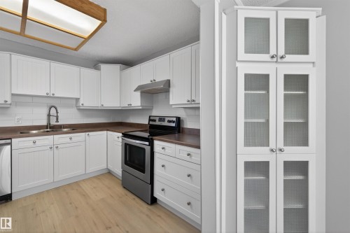 Bright kitchen featuring white cabinetry, wood-finish flooring, and a subway tile backsplash - 11 Greenfield Estates, St. Albert, AB - Indoor Photo Showing Kitchen With Double Sink