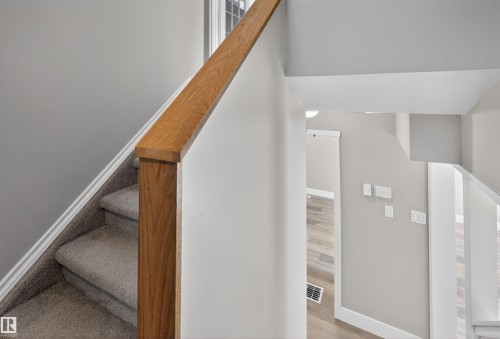 Carpeted staircase with a wood-finish handrail and banister - 11 Greenfield Estates, St. Albert, AB - Indoor Photo Showing Other Room