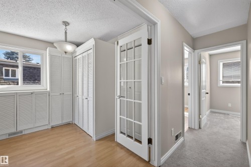 Room featuring wood-finish flooring, white louvered cabinetry, and a pendant light fixture - 11 Greenfield Estates, St. Albert, AB - Indoor Photo Showing Other Room