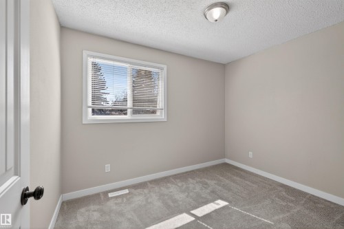 Neutral-toned room featuring a window with horizontal blinds, textured ceiling, and gray carpet flooring - 11 Greenfield Estates, St. Albert, AB - Indoor Photo Showing Other Room