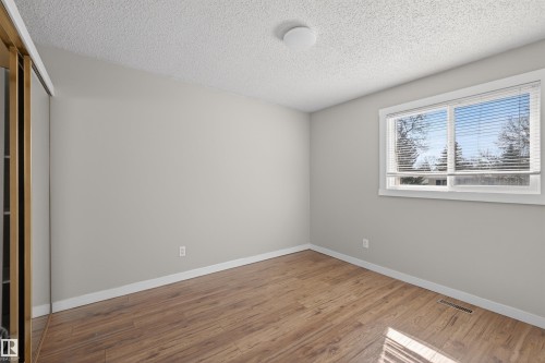 Bright room featuring wood-finish flooring, light grey painted walls, and a large window with white blinds - 11 Greenfield Estates, St. Albert, AB - Indoor Photo Showing Other Room