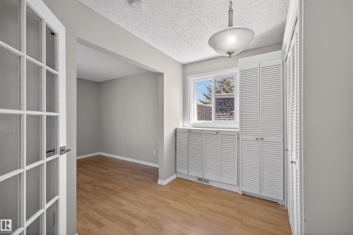 Room featuring wood-finish flooring, a window with exterior visibility, and white louvered cabinetry - 11 Greenfield Estates, St. Albert, AB - Indoor Photo Showing Other Room
