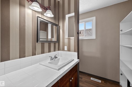 Bathroom vanity with integrated sink, chrome faucet, and white tiled countertop - 11 Greenfield Estates, St. Albert, AB - Indoor Photo Showing Bathroom