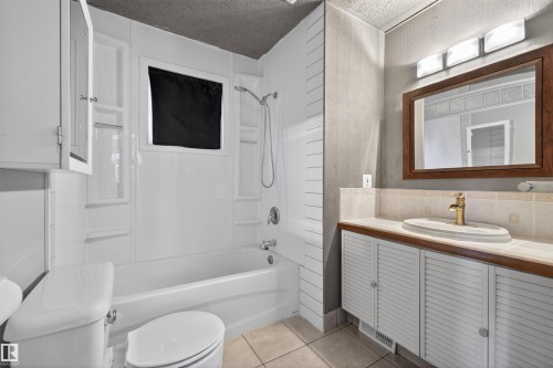 Full bathroom featuring a white tub and shower surround, a white toilet, and a vanity with a white vessel sink - 11 Greenfield Estates, St. Albert, AB - Indoor Photo Showing Bathroom