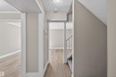 Hallway featuring wood-finish flooring, light grey painted walls, white trim, and a carpeted staircase with white balusters - 11 Greenfield Estates, St. Albert, AB  - Indoor 