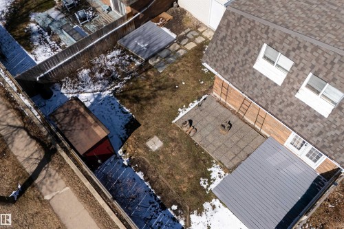 Rear exterior featuring a brown shingle roof, light brick siding, and a ground-level patio - 11 Greenfield Estates, St. Albert, AB - 