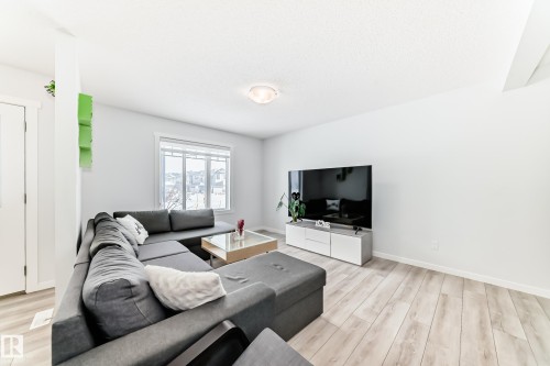 Bright living space featuring light wood-finish flooring, a large window, and an open layout - 2505 14 Avenue, Edmonton, AB - Indoor Photo Showing Living Room