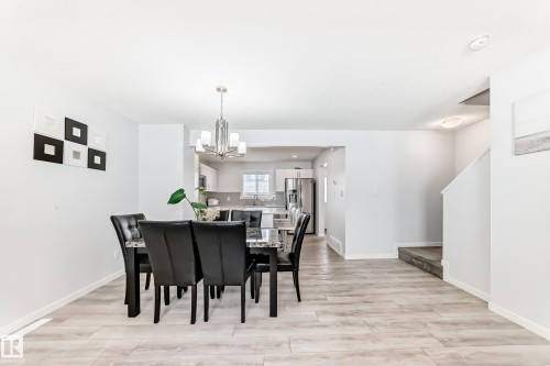 Dining area featuring wood-finish flooring, a contemporary chandelier, and a pass-through opening to the kitchen - 2505 14 Avenue, Edmonton, AB - Indoor Photo Showing Dining Room