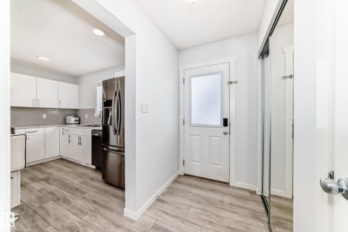 Entryway with wood-finish flooring, a white paneled door with frosted glass, and mirrored closet doors - 2505 14 Avenue, Edmonton, AB - Indoor Photo Showing Other Room