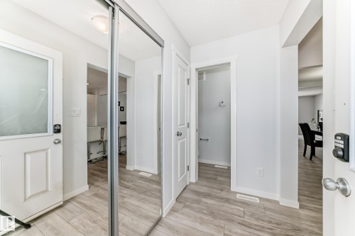 Entryway featuring wood-finish flooring, a white paneled door with frosted glass, and a full-height mirrored closet - 2505 14 Avenue, Edmonton, AB - Indoor Photo Showing Other Room
