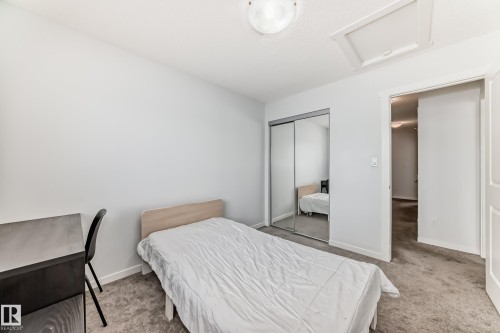 Carpeted room featuring a ceiling-mounted light fixture, an attic access panel, and a mirrored sliding closet door - 2505 14 Avenue, Edmonton, AB - Indoor Photo Showing Bedroom