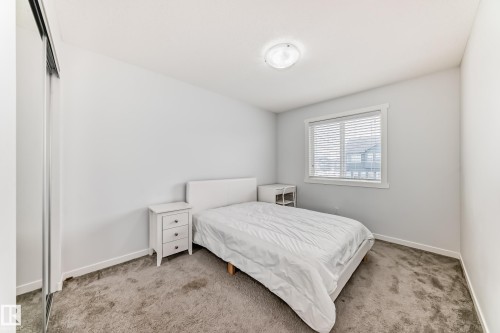 Carpeted bedroom featuring a large window with horizontal blinds, a white trim package, and a flush-mount ceiling light - 2505 14 Avenue, Edmonton, AB - Indoor Photo Showing Bedroom