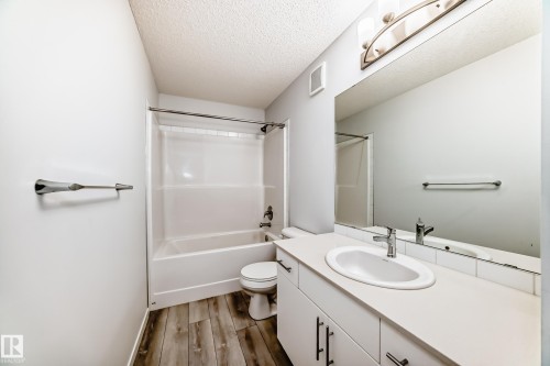 Bathroom featuring a single vanity with an integrated sink, chrome faucet, and expansive wall-mounted mirror - 2505 14 Avenue, Edmonton, AB - Indoor Photo Showing Bathroom