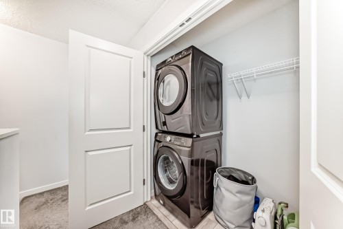 Dedicated laundry closet featuring a stacked washer and dryer, practical wire shelving, and light-toned wall paint - 2505 14 Avenue, Edmonton, AB - Indoor Photo Showing Laundry Room
