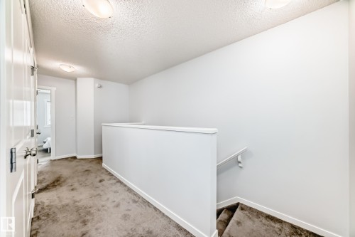Upper-level hallway with neutral carpeting, white trim, and doors with panel detailing - 2505 14 Avenue, Edmonton, AB - Indoor Photo Showing Other Room