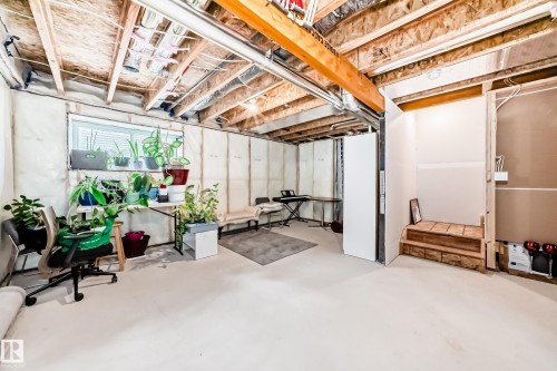 Unfinished basement featuring exposed wood joists and structural beams, a visible window, insulated walls, and a partial staircase - 2505 14 Avenue, Edmonton, AB - Indoor Photo Showing Basement