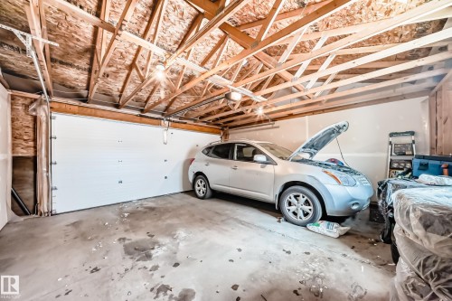 Spacious garage with exposed wood beam ceiling, concrete flooring, and a white panel garage door - 2505 14 Avenue, Edmonton, AB - Indoor Photo Showing Garage