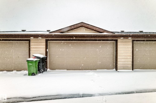 Three individual garage doors with horizontal paneling, tan siding, and a brown trimmed roofline - 2505 14 Avenue, Edmonton, AB - Outdoor