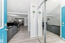Entryway featuring a bright blue door with frosted glass, wood-finish flooring, a mirrored closet, and a clear line of sight into the kitchen and dining areas - 2505 14 Avenue, Edmonton, AB  - Indoor Photo Showing Other Room 
