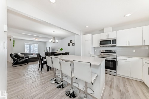 Kitchen featuring white cabinetry, light-toned countertops, stainless steel appliances, and a tiled backsplash - 2505 14 Avenue, Edmonton, AB - Indoor Photo Showing Kitchen