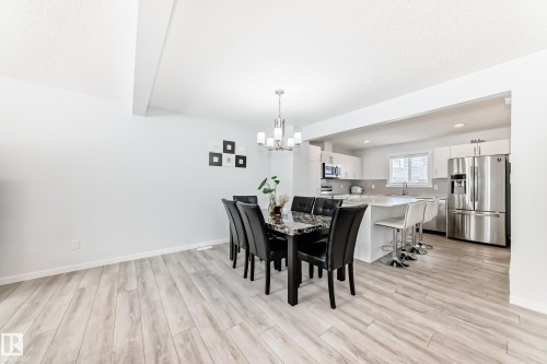 Open-concept layout featuring wood-finish flooring, a contemporary dining area with a chandelier, and a kitchen with stainless steel appliances - 2505 14 Avenue, Edmonton, AB - Indoor Photo Showing Dining Room