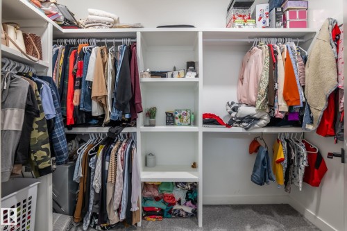 Walk-in closet featuring built-in white shelving, multiple hanging rods, and recessed lighting - 6607 50A Avenue, Beaumont, AB - Indoor With Storage