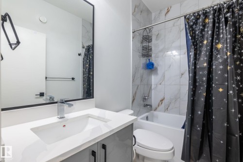 Bathroom featuring a white integrated sink, chrome faucet, and a large rectangular mirror with a black frame - 6607 50A Avenue, Beaumont, AB - Indoor Photo Showing Bathroom