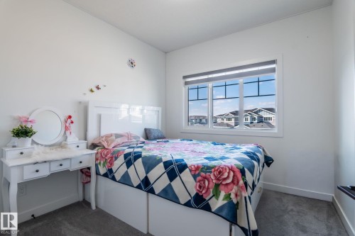 Spacious bedroom featuring clean white walls, a large window with horizontal blinds, and grey carpeting - 6607 50A Avenue, Beaumont, AB - Indoor Photo Showing Bedroom