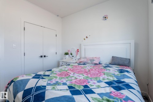 White painted walls with a white paneled headboard and double closet doors featuring black hardware - 6607 50A Avenue, Beaumont, AB - Indoor Photo Showing Bedroom