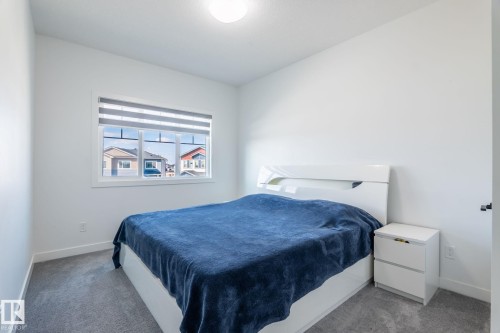 White-painted interior room featuring a window with horizontal blinds, grey carpeting, a flush-mount ceiling light fixture, and white baseboards - 6607 50A Avenue, Beaumont, AB - Indoor Photo Showing Bedroom