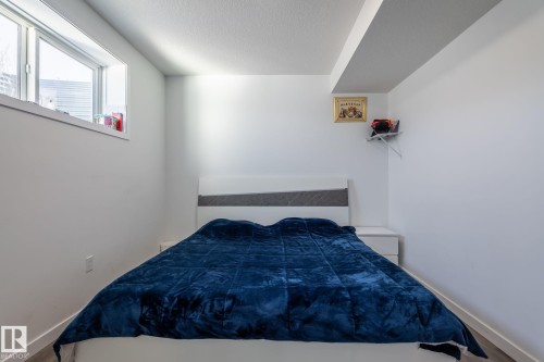 Room featuring a large window, white walls, and wood-finish flooring - 6607 50A Avenue, Beaumont, AB - Indoor Photo Showing Bedroom