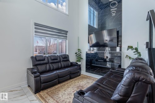 High ceilings complement a contemporary feature wall with a black marble-effect finish and integrated television - 6607 50A Avenue, Beaumont, AB - Indoor Photo Showing Living Room With Fireplace