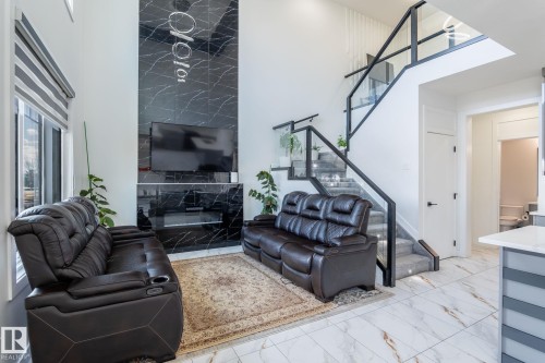 Two-story living area featuring a black marble-look accent wall with a built-in electric fireplace - 6607 50A Avenue, Beaumont, AB - Indoor Photo Showing Other Room