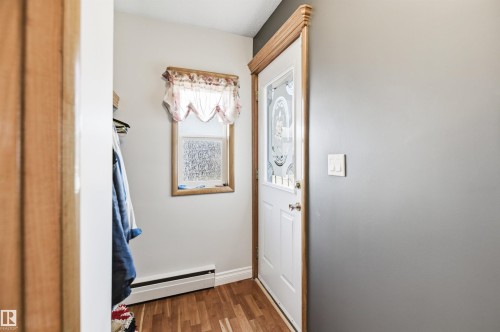 Entryway featuring wood-finish flooring, a white paneled door with decorative glass inserts, and wood trim - 3920 35A Avenue, Red Deer, AB - Indoor Photo Showing Other Room