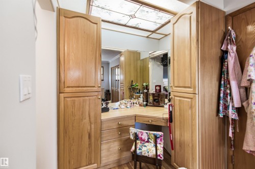 Built-in vanity area featuring wood-finish cabinetry, a mirrored wall, and a wood-finish countertop - 3920 35A Avenue, Red Deer, AB - Indoor