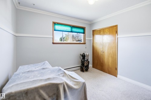 Light-filled room featuring a wood-trimmed window, neutral wall paint, white crown molding, and light-colored carpeting - 3920 35A Avenue, Red Deer, AB - Indoor Photo Showing Bedroom