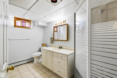 Bathroom featuring a walk-in shower with frosted glass doors, a vanity with a light-toned countertop and integrated sink, and an overhead drop ceiling - 3920 35A Avenue, Red Deer, AB - Indoor Photo Showing Bathroom