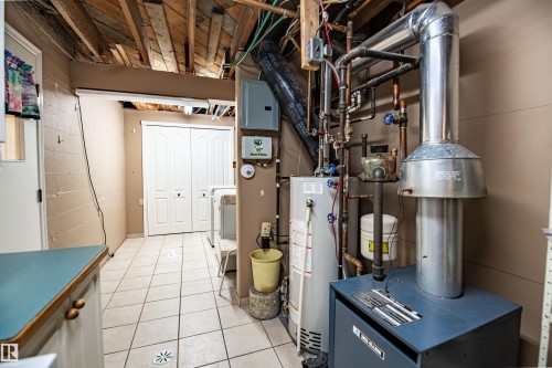 Utility area with exposed wood ceiling beams, a water heater, and a furnace system - 3920 35A Avenue, Red Deer, AB - Indoor Photo Showing Basement